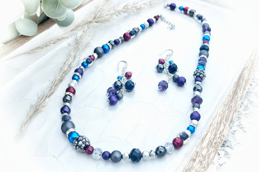 Beaded necklace and earrings set on a textured surface